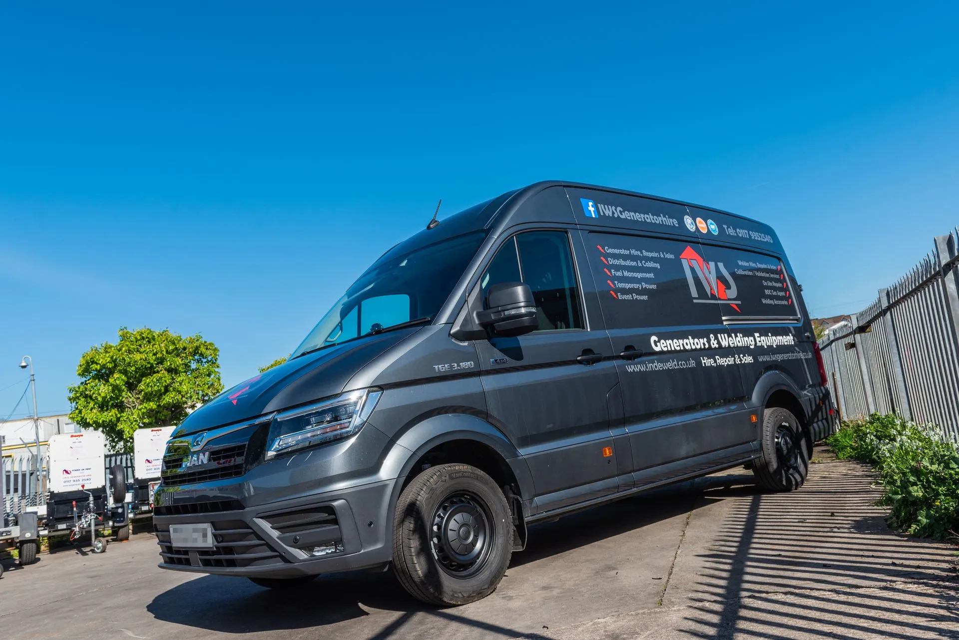 A van parked in a parking lot next to a fence.