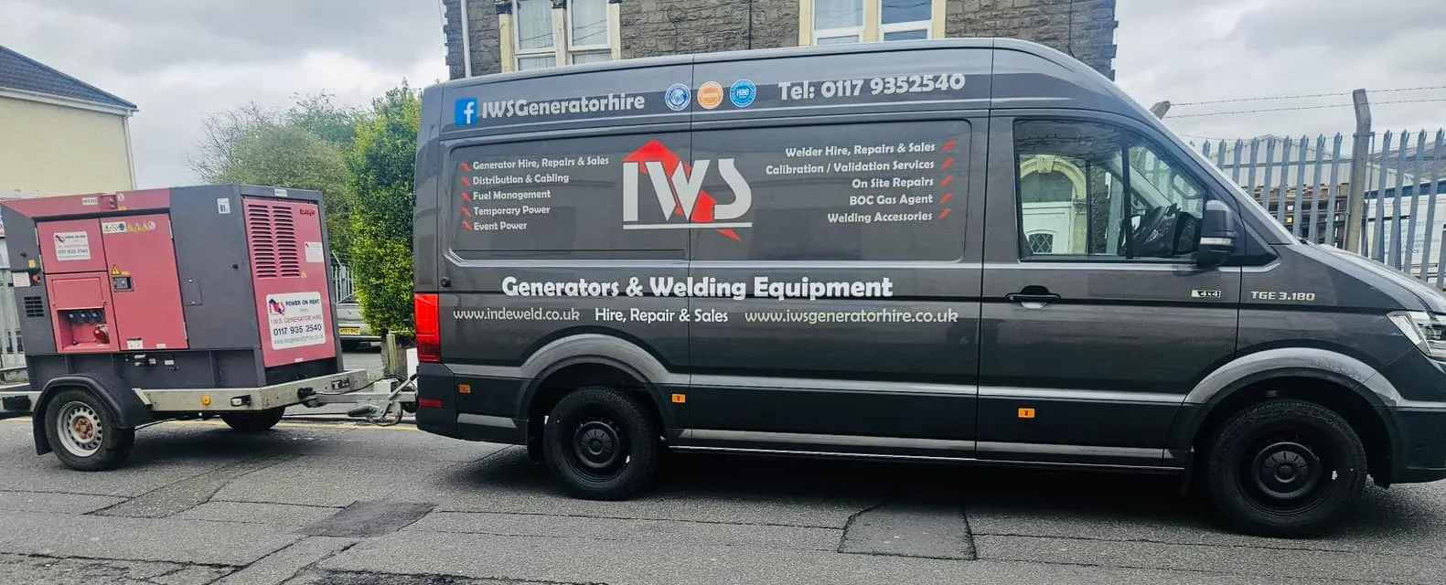 A black van parked next to a red trailer.